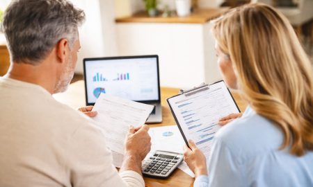 Personas revisando cuentas de inversión en una laptop y documentos financieros, como parte de educación financiera y planificación patrimonial mediante designación TOD (Transfer on Death).