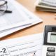 Temporada de impuestos 2026: Formulario W-2 parcialmente visible junto a una calculadora y lápiz sobre un escritorio.